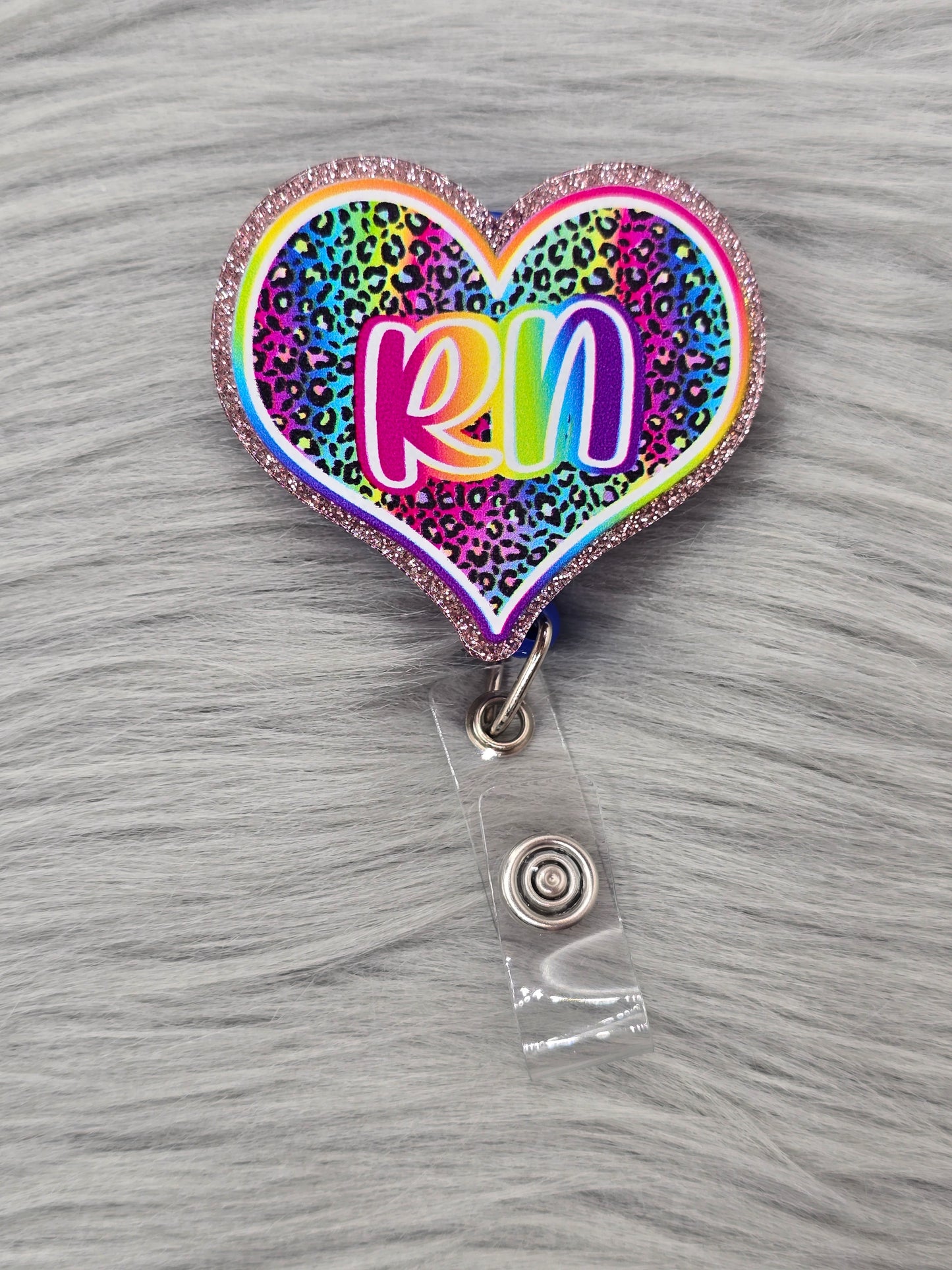Heart shaped acrylic flatback with a rainbow leopard background and the letters RN in rainbow