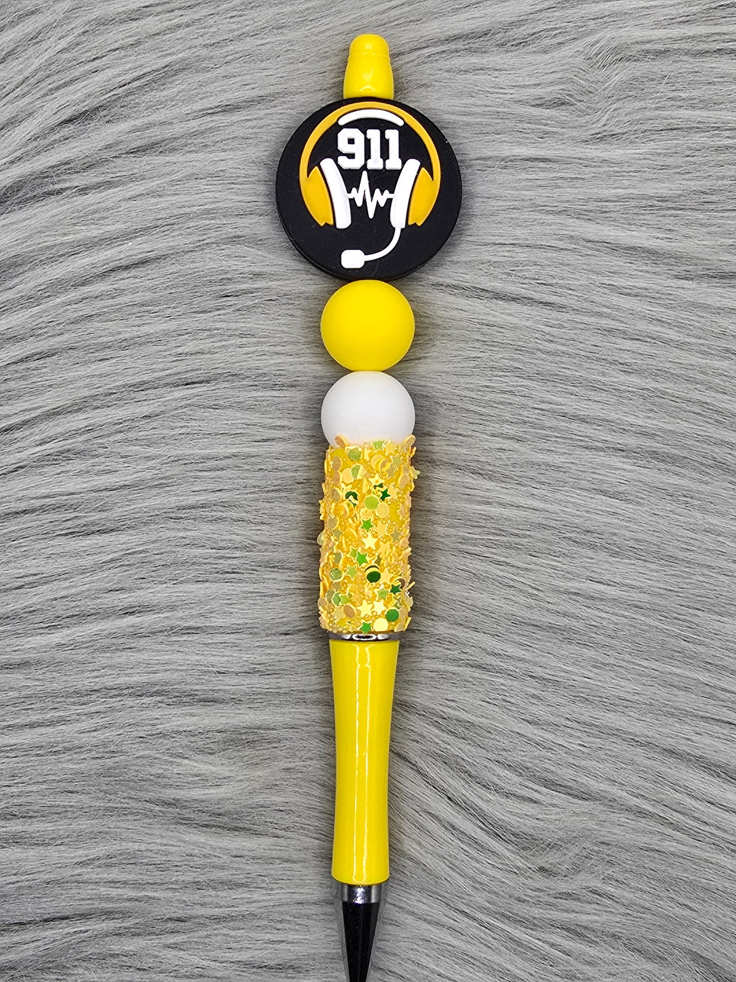 Yellow glitter beadable pen with a silicone focal that says 911 with a headset and a yellow and white bead