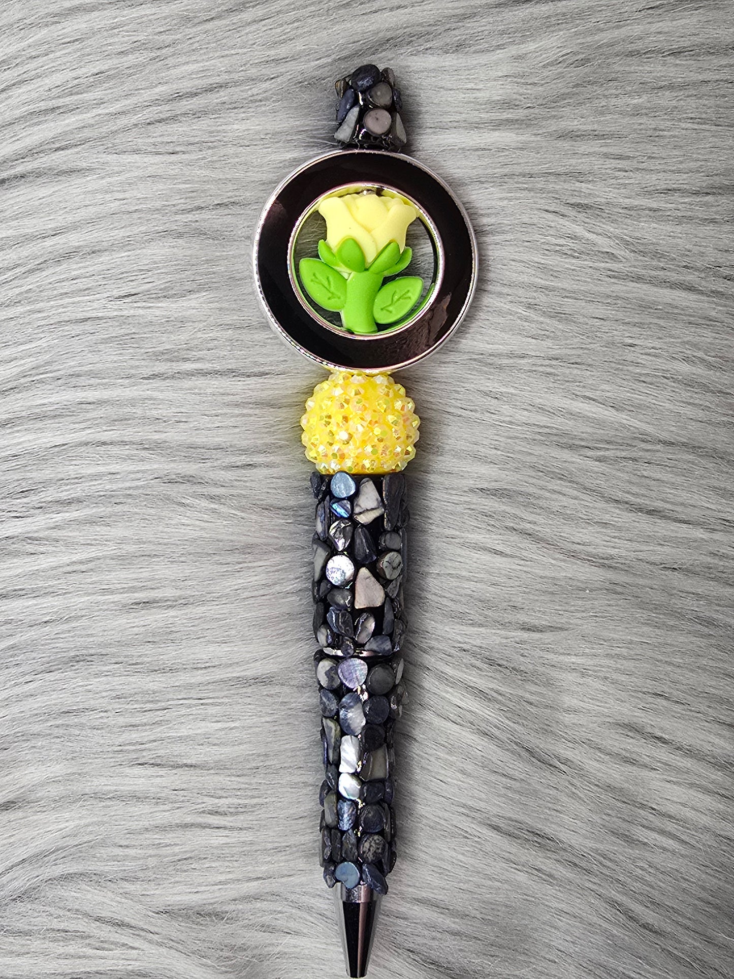 Black beadable pen with pebbles, yellow rhinestone bead with a yellow flower in a black ring at the top
