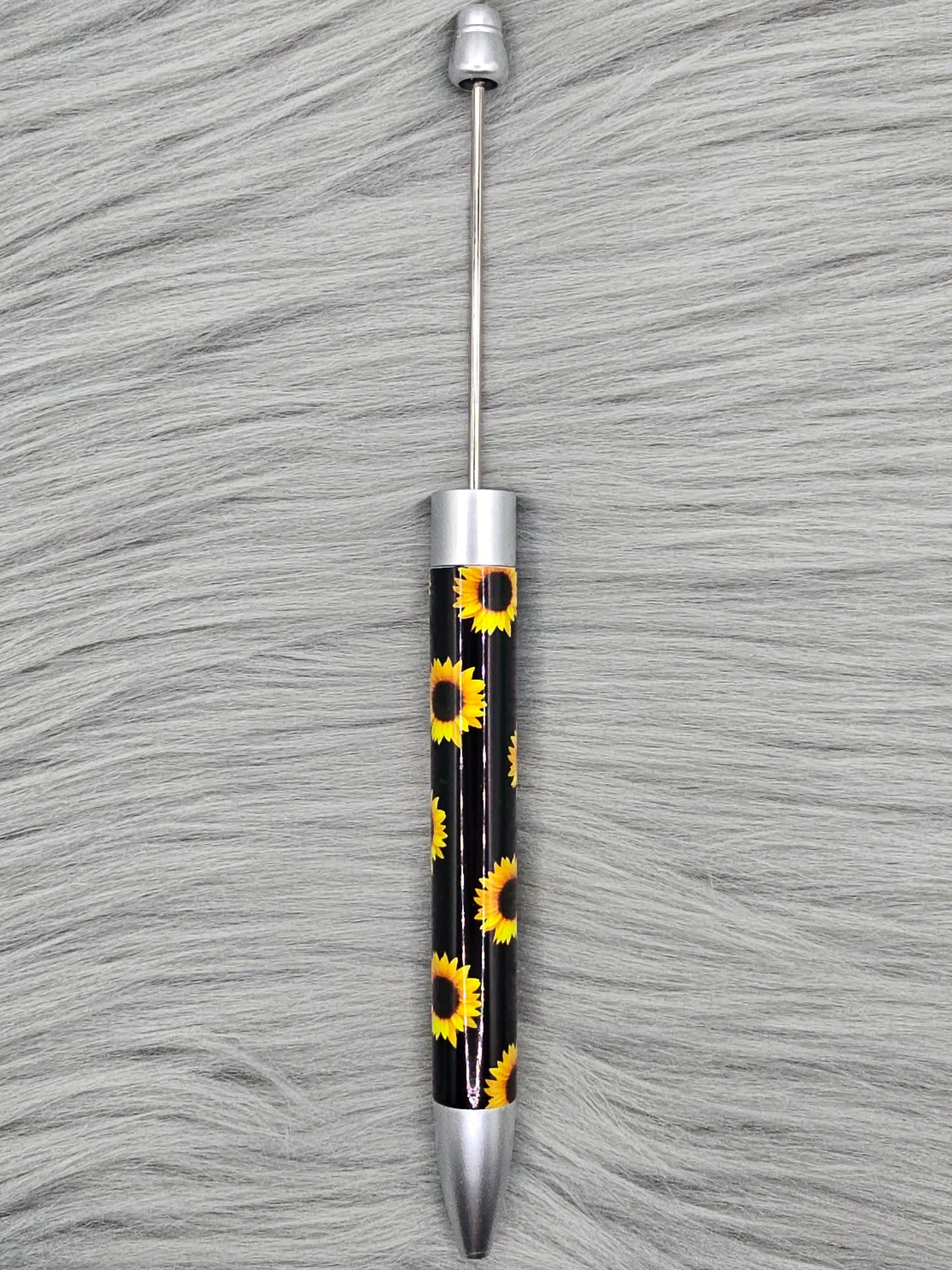 Black beadable pen with sunflower pattern on a gray fur surface