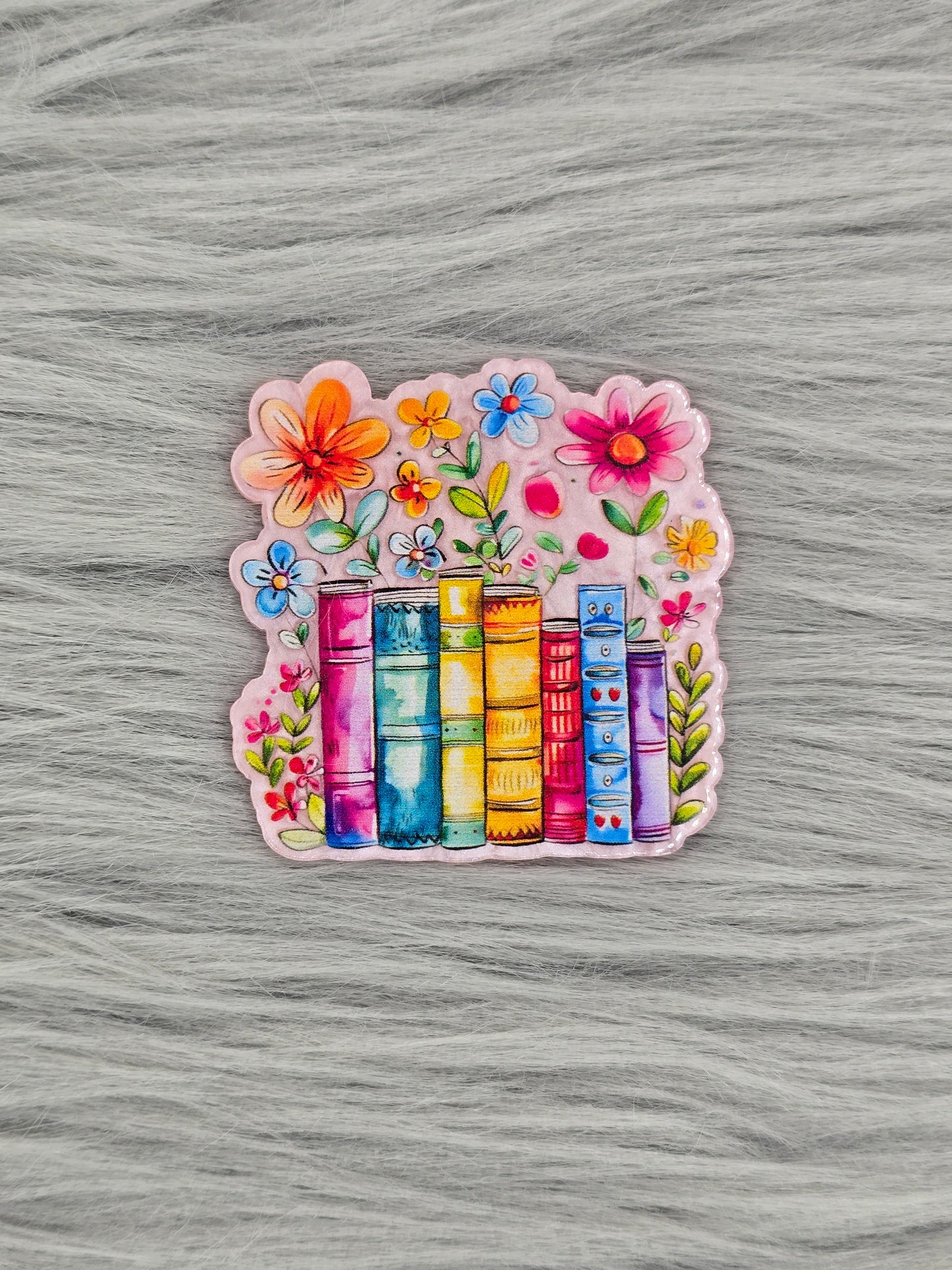 Colorful acrylic flatback with books and flowers on a gray textured background