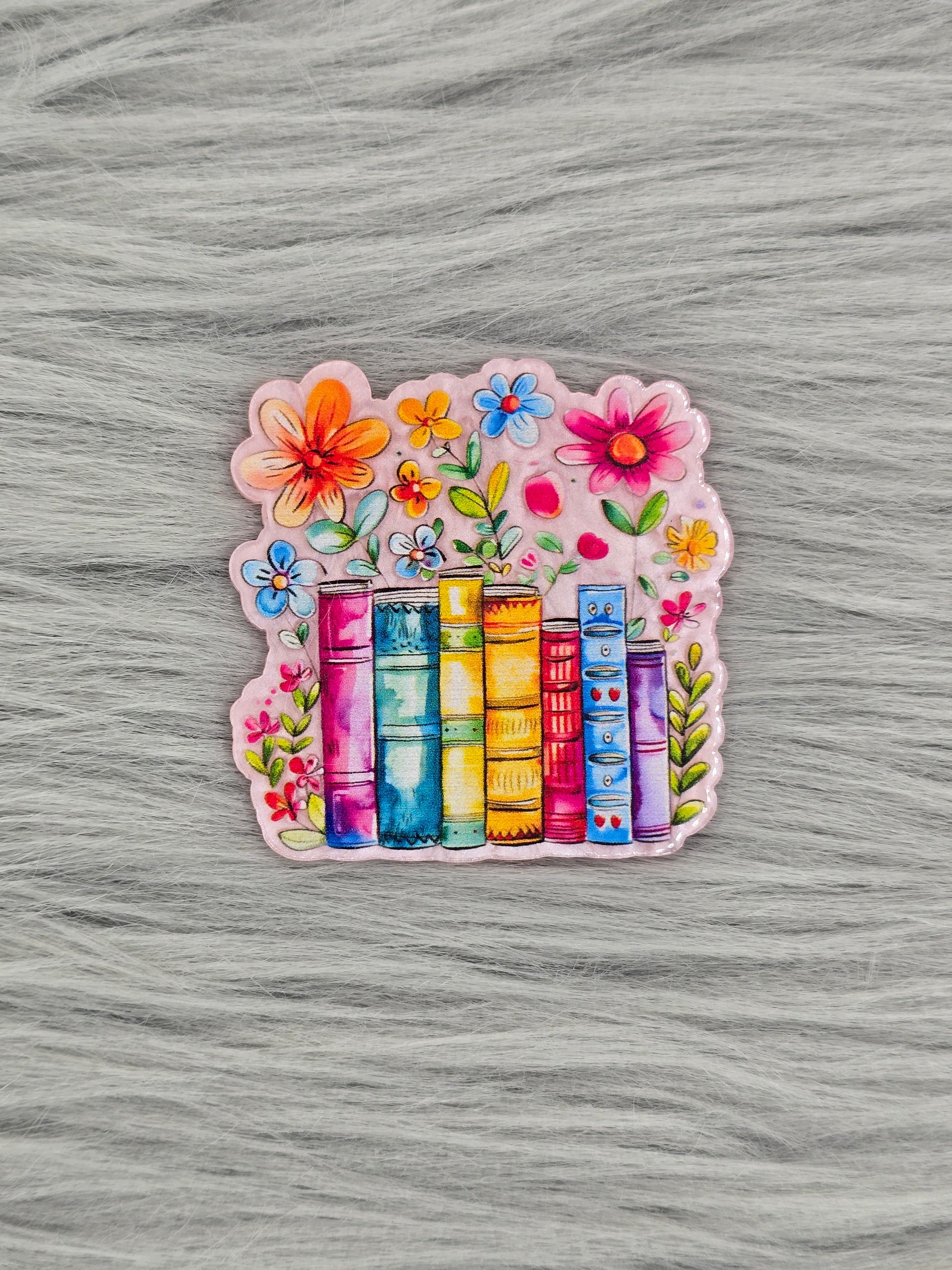 Colorful acrylic flatback with books and flowers on a gray textured background