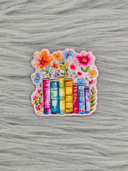 Colorful acrylic flatback with books and flowers on a gray textured background