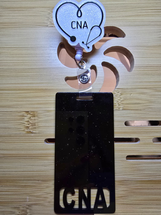 White acrylic flatback with the words CNA in back and a stethoscope in a heart with a black long badge buddy that says CNA