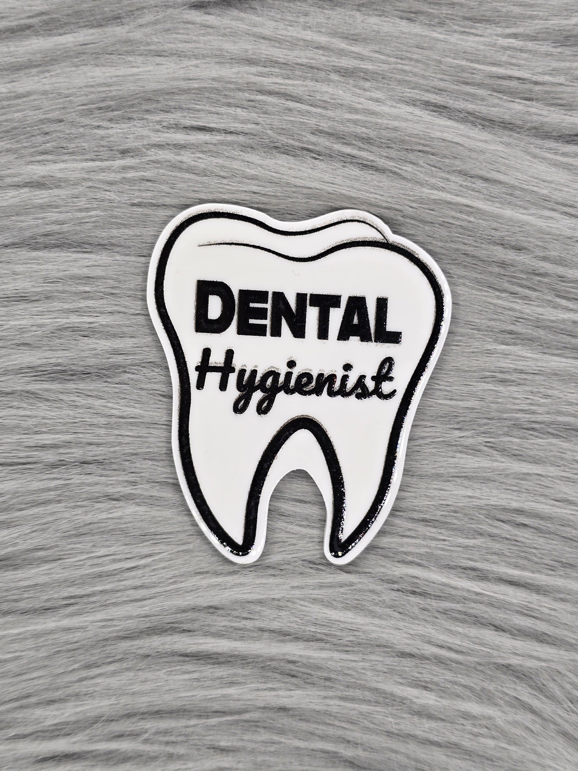 White Acrylic flatback in the shape of a tooth that says 'Dental Hygienist' in black 