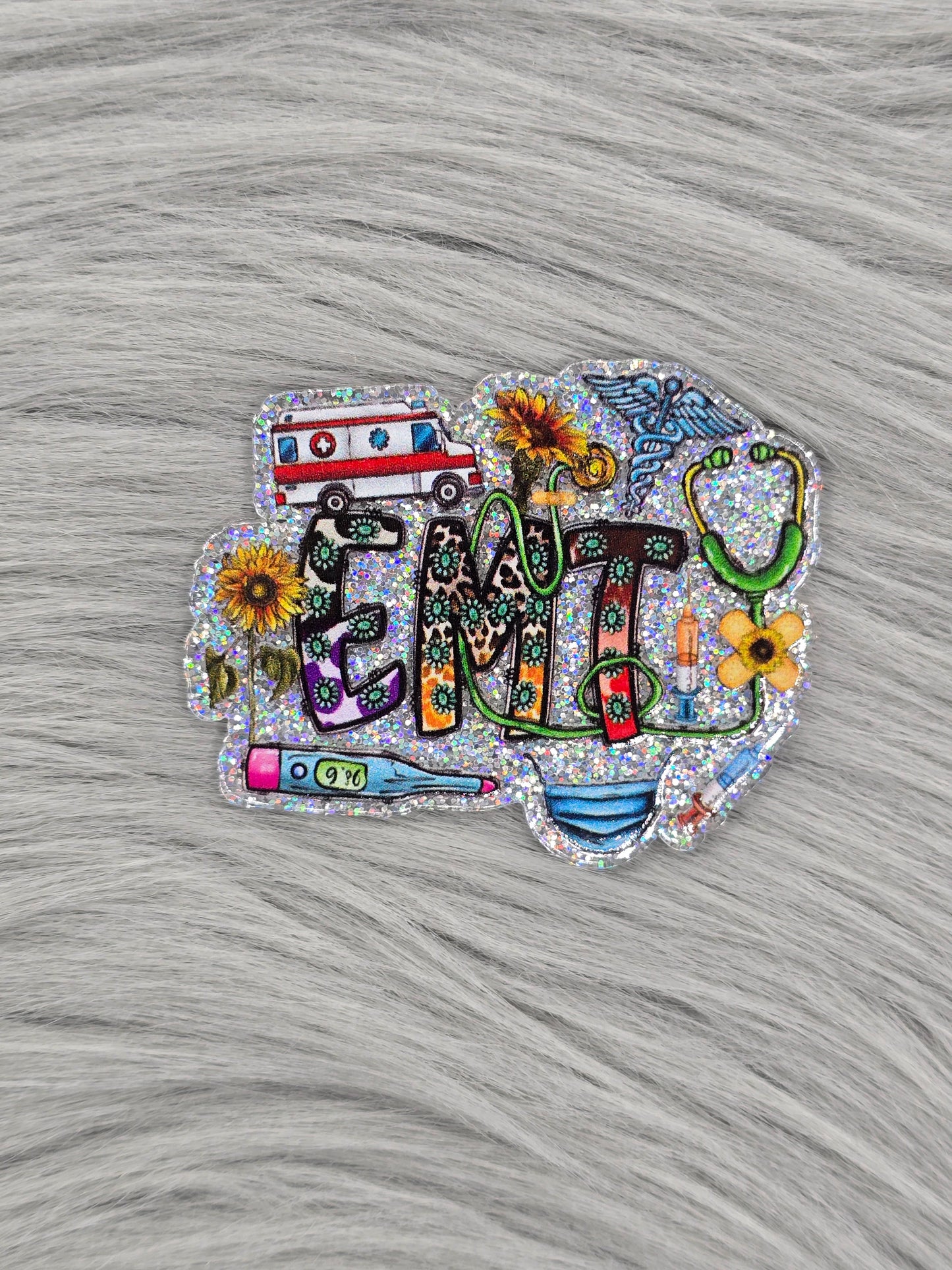 Silver glitter background acrylic flatback with the letters 'EMT' with medical items and yellow flowers