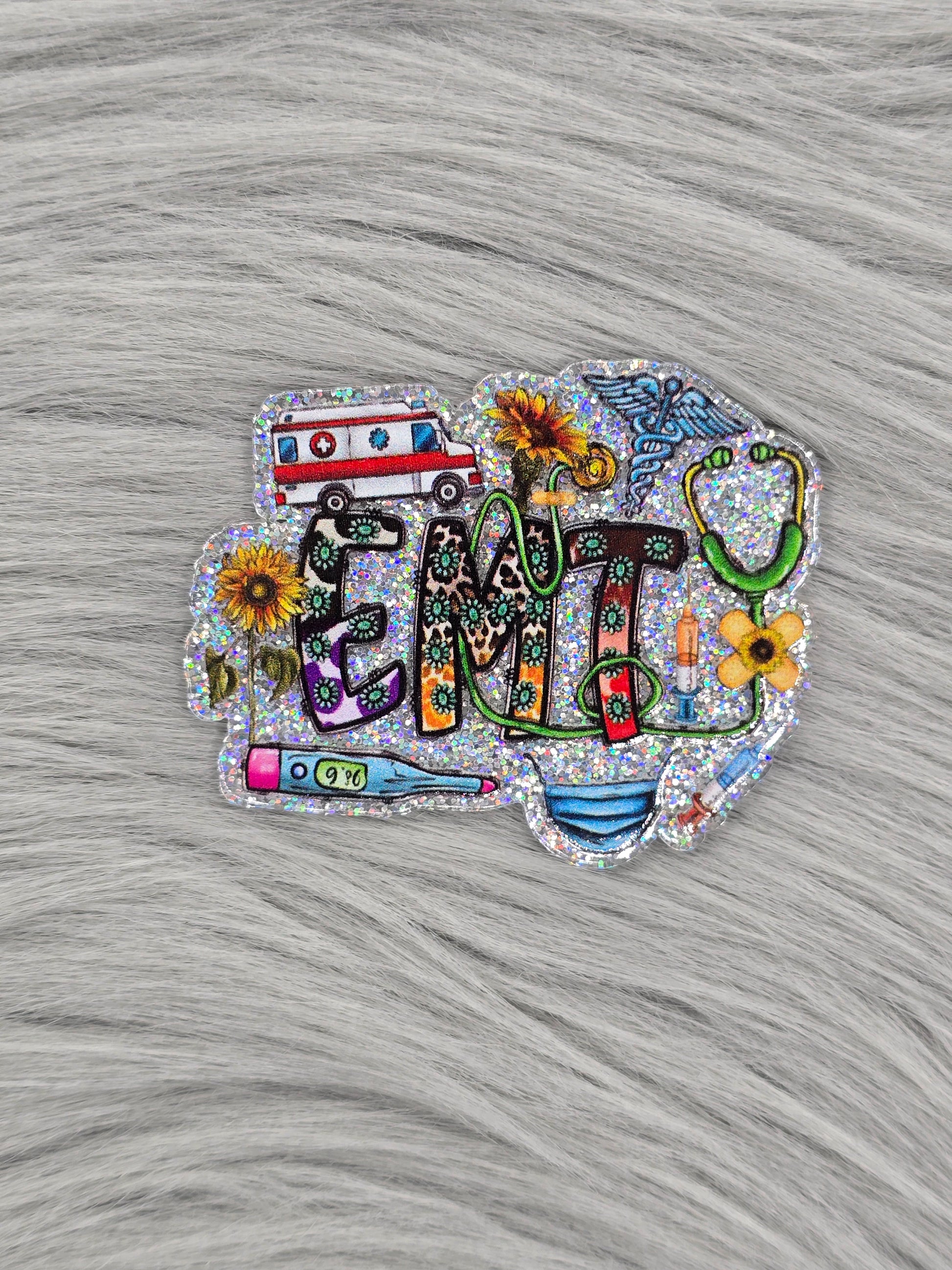 Silver glitter background acrylic flatback with the letters 'EMT' with medical items and yellow flowers