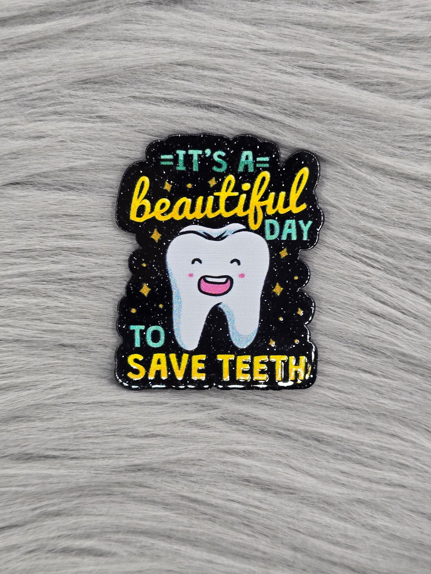 Black glitter acrylic flatback with the words "It's A Beautiful Day To Save Teeth" in green and yellow with a tooth in the middle