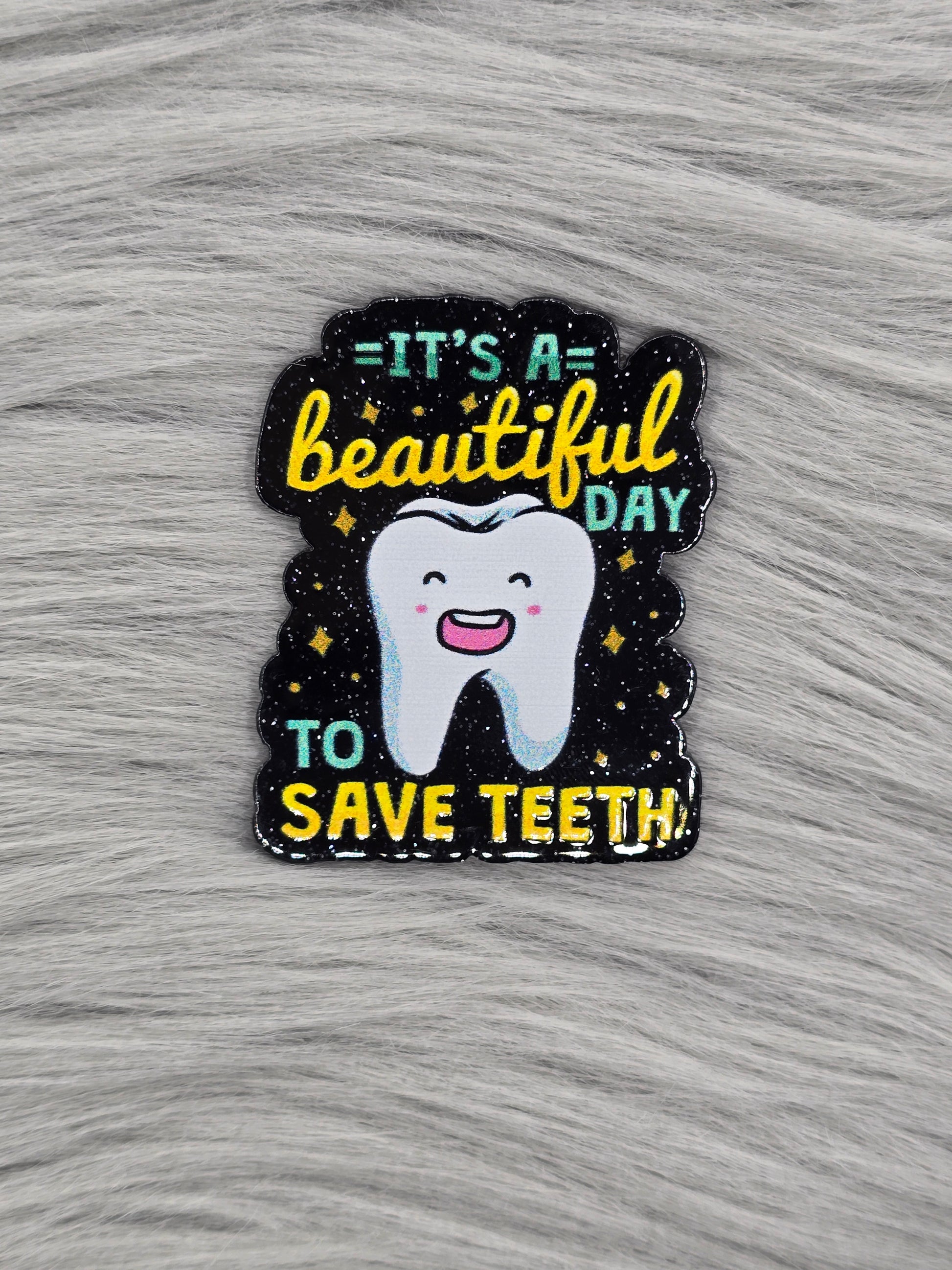 Black glitter acrylic flatback with the words "It's A Beautiful Day To Save Teeth" in green and yellow with a tooth in the middle