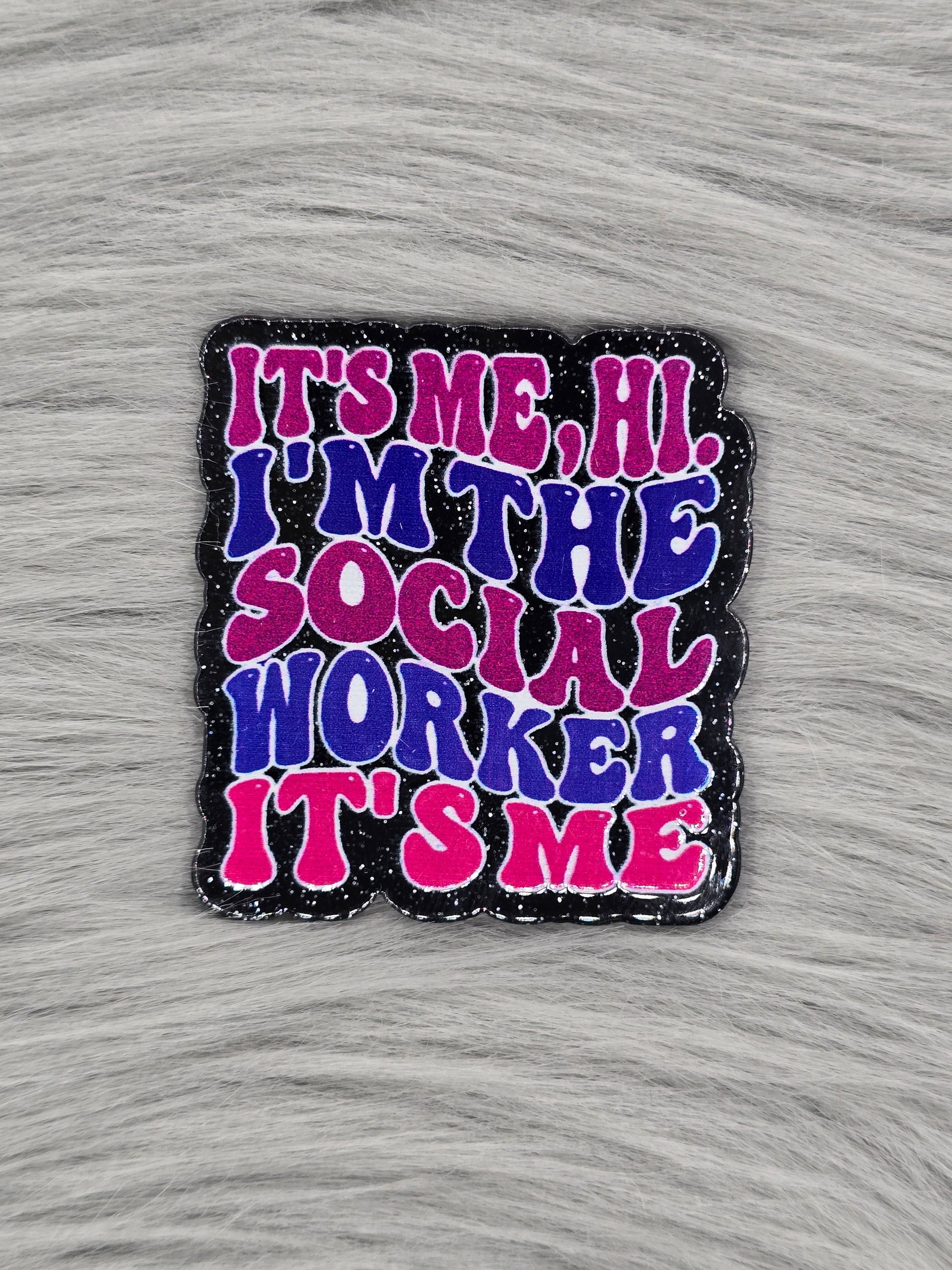Acrylic flatback with glitter black background and the words 'It's Me, Hi I'm The Social Worker It's Me' in pink and blue