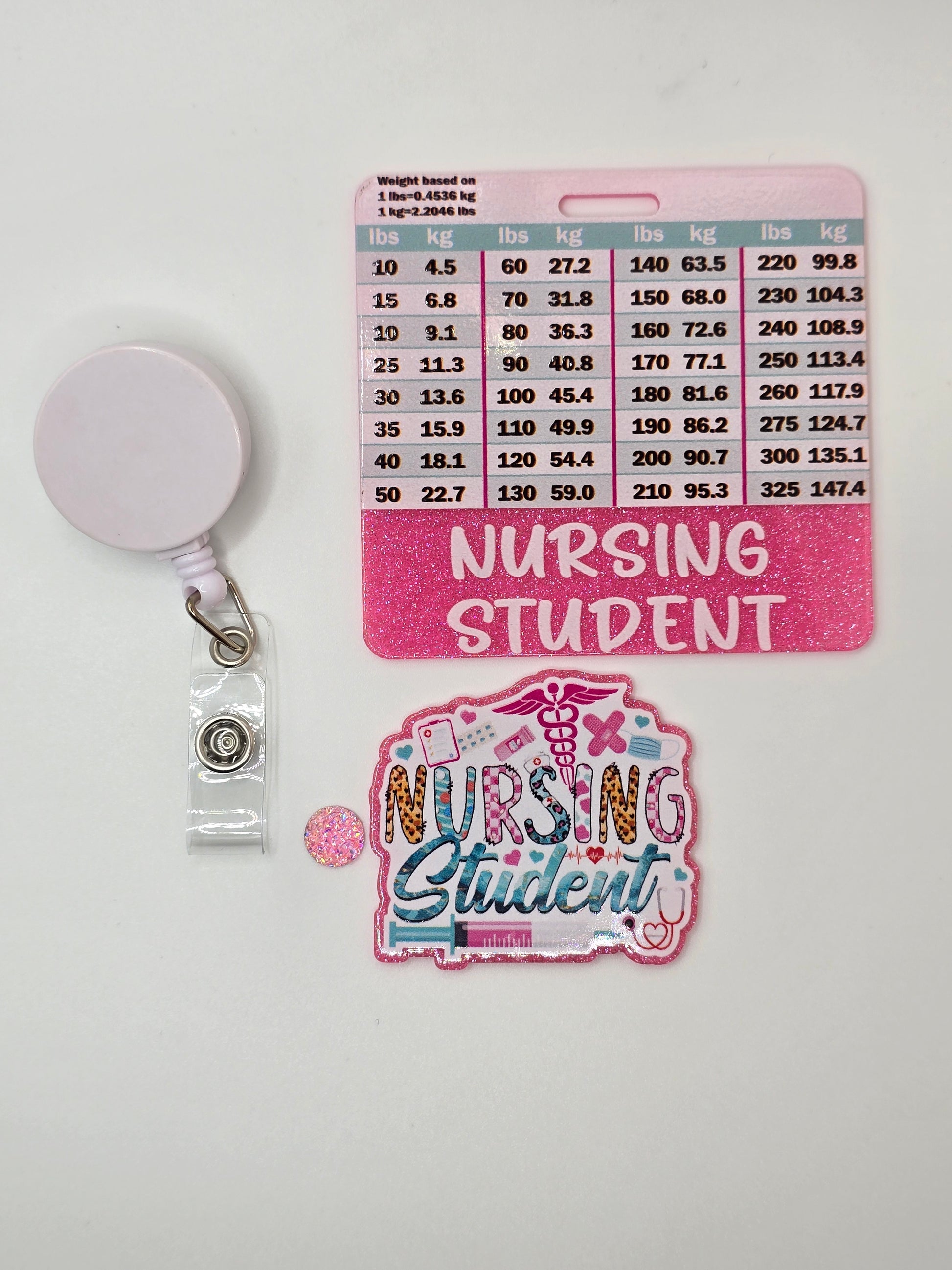 Badge reel with a pink Nursing Student Badge Buddy and decorative glitter flatback that says Nursing Student on a white background