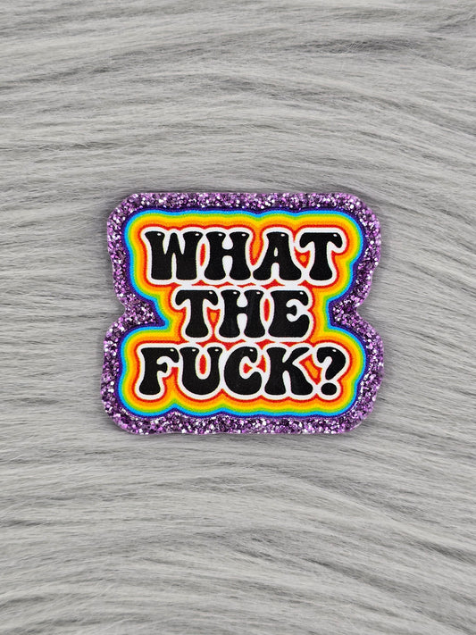 Purple Glitter flatback with a rainbow background and black words that say "What The Fuck?"