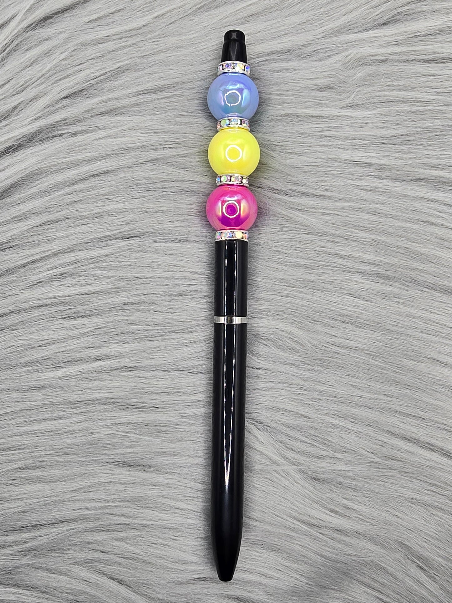 Black beadable pen with silver rhinestone spaces and a pink, yellow and blue bead