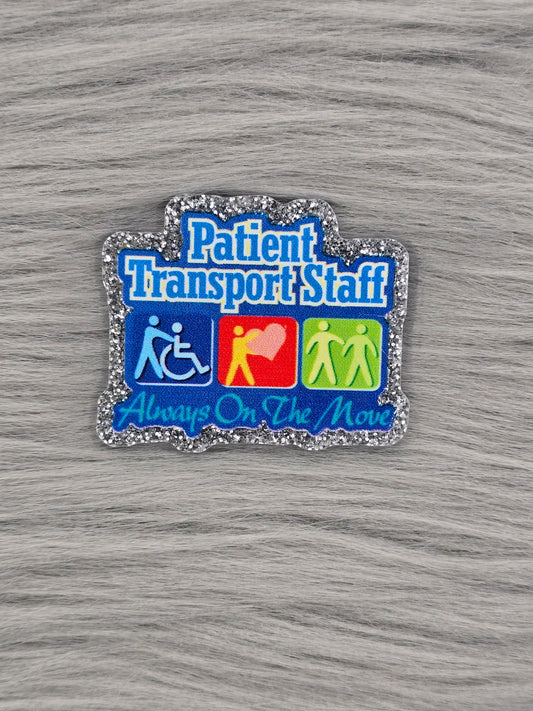Acrylic flatback with a silver background and blue words that say "Patient Transport Staff Always On The Move" With 3 pictures of a silhouette person