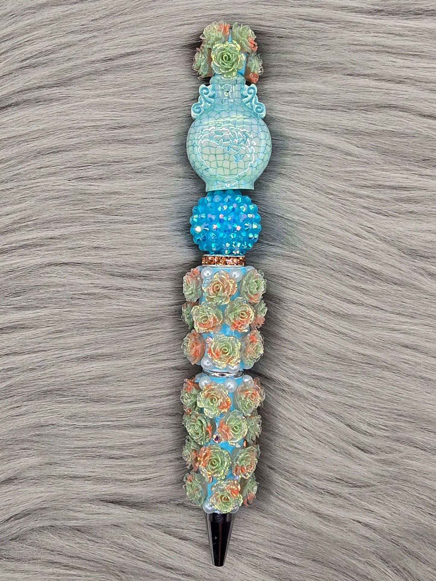Light blue beadable pen pen with light orange/light green flowers with a blue rhinestone bead, light blue vase at the top