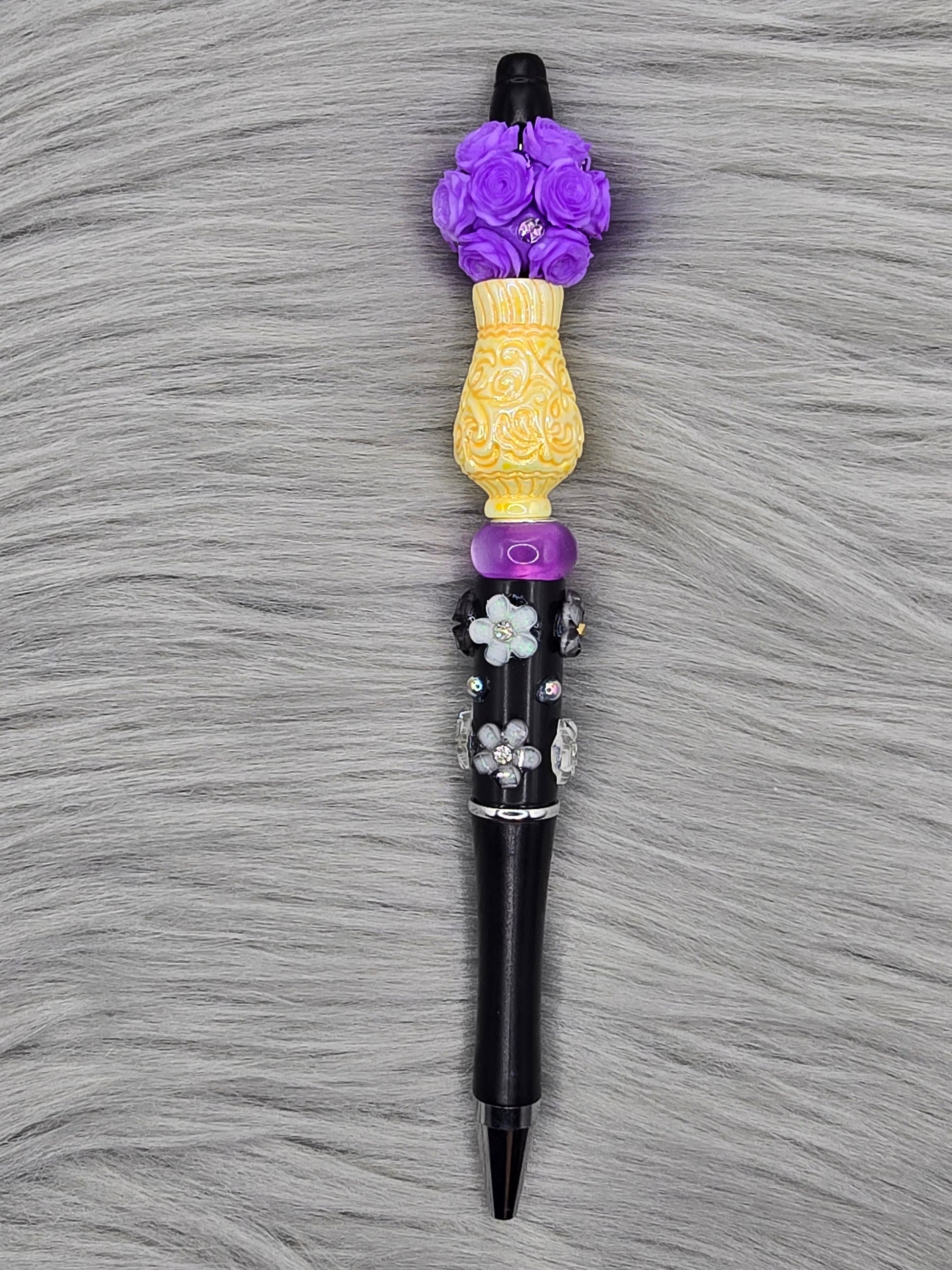 Black beadable pen with white flowers, yellow vase focal and a purple flower bead at the top