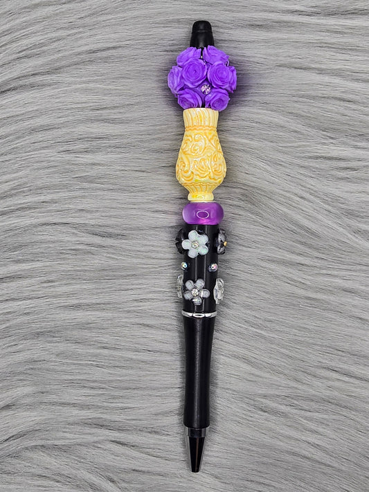 Black beadable pen with white flowers, yellow vase focal and a purple flower bead at the top