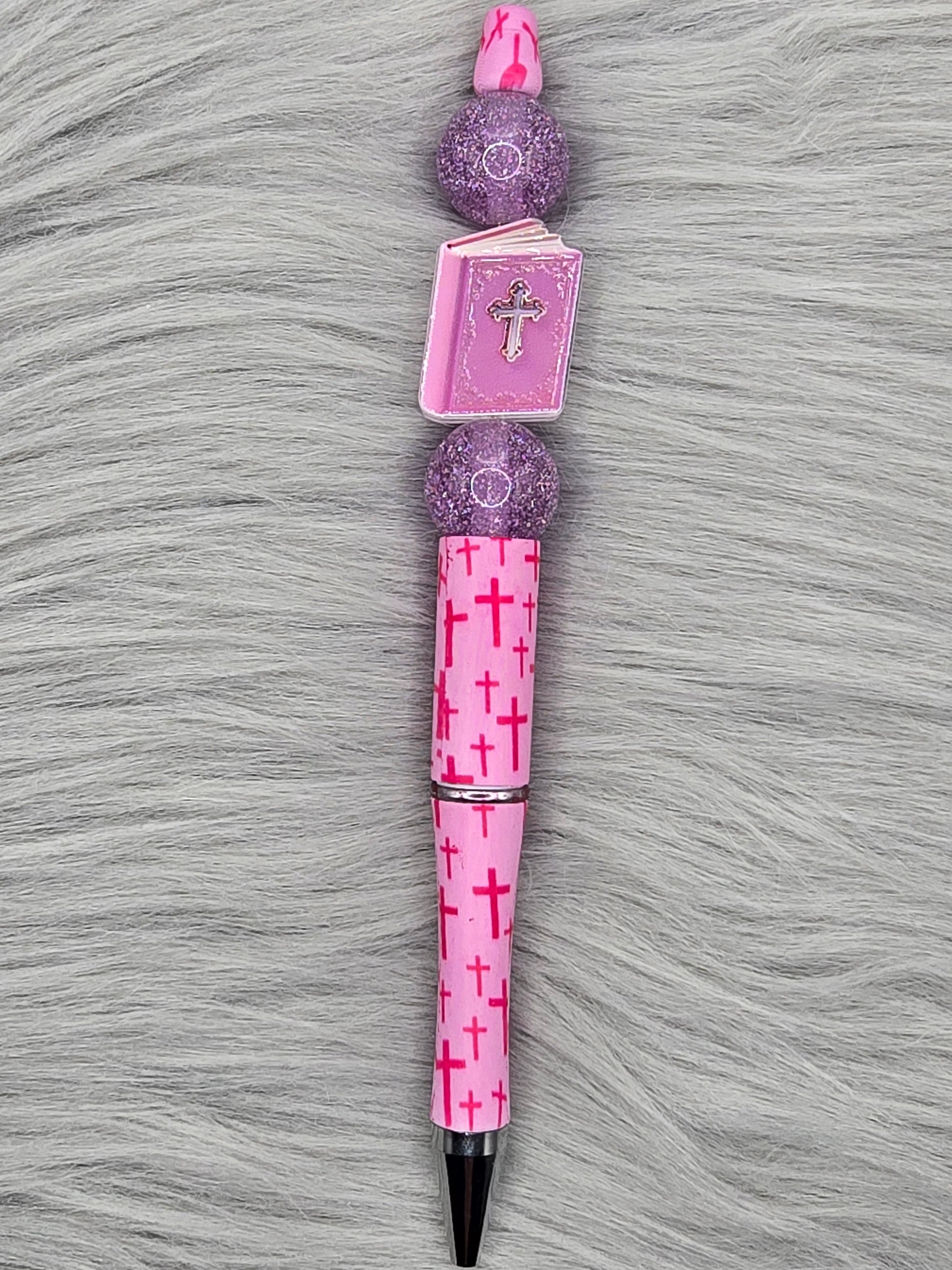 Pink beadabale pen with dark pink crosses with a pink bible with a silver cross and 2 glitter purple beads