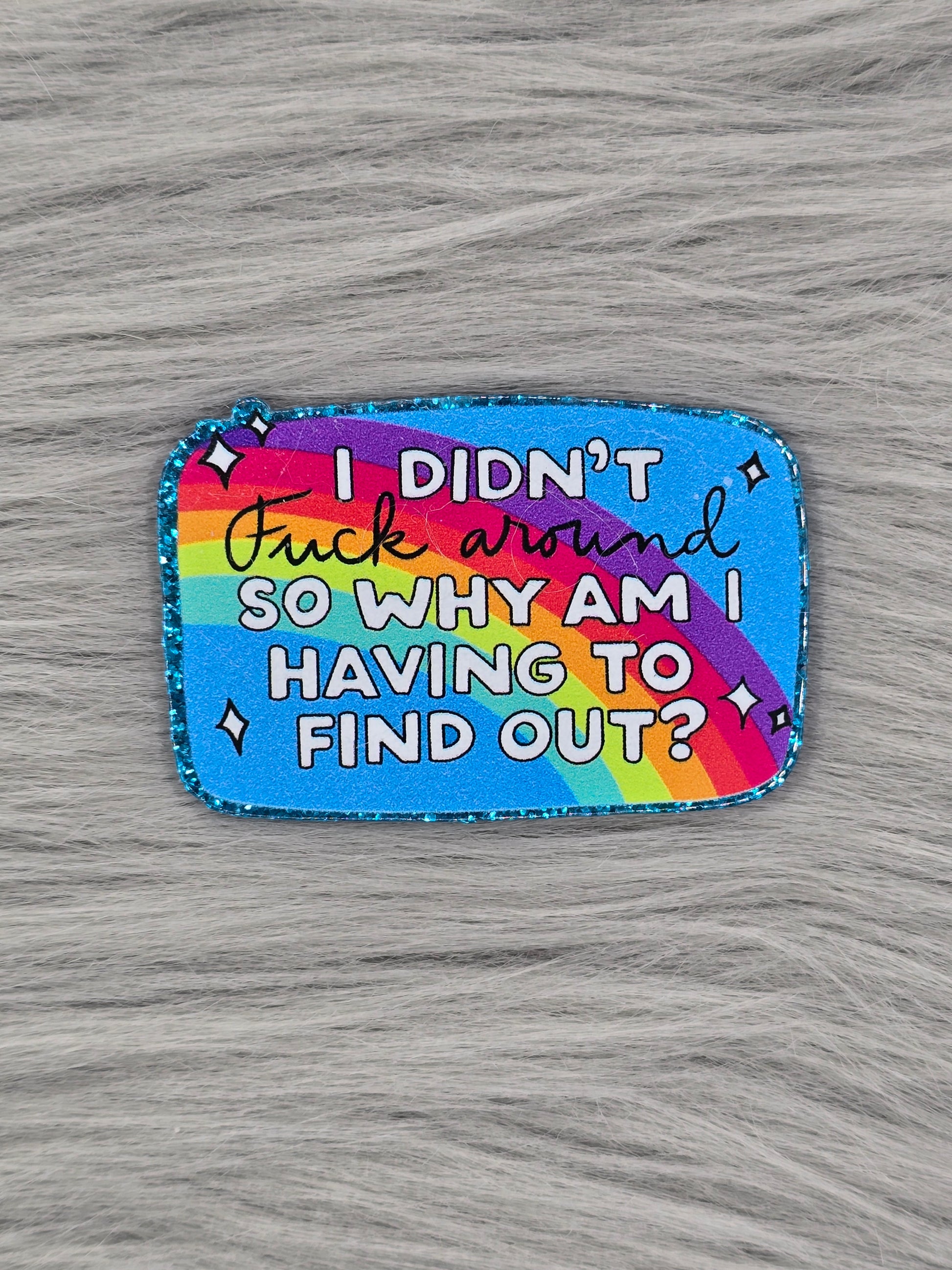 Acylic flatback with a blue background with a rainbow that says "I Didn't Fuck Around So Why Am I Having To Find Out?"