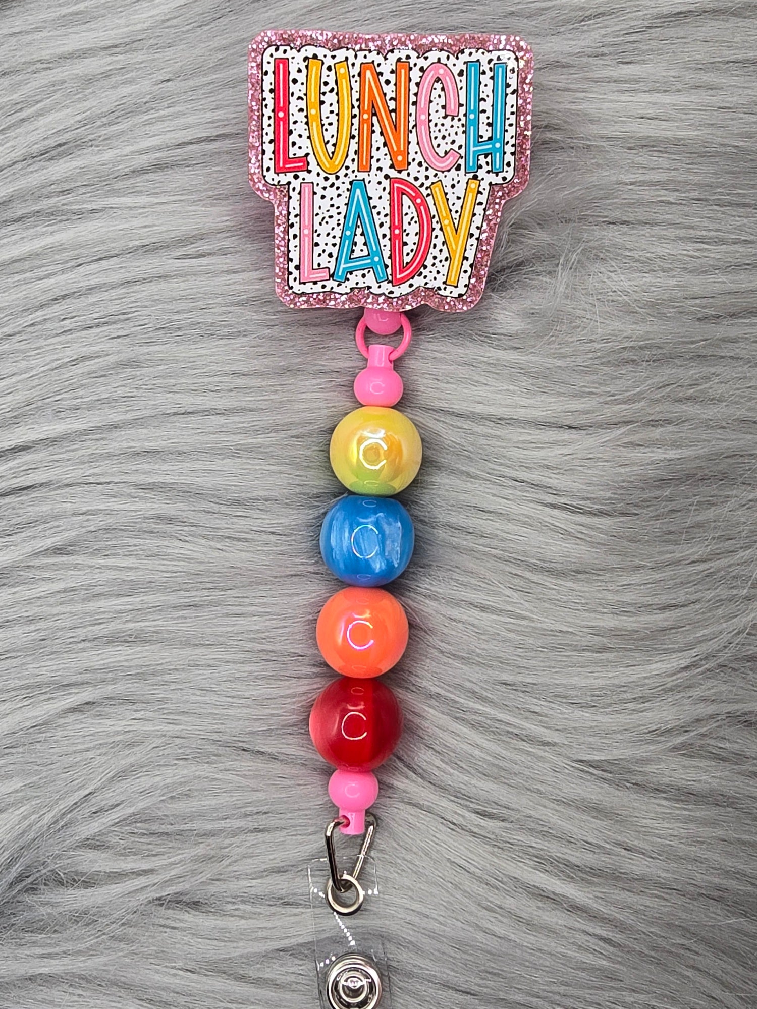 Acrylic flatback with the word lunch lady on a polk-a-dot back ground with 4 beads hanging down in yellow, blue, orange and red