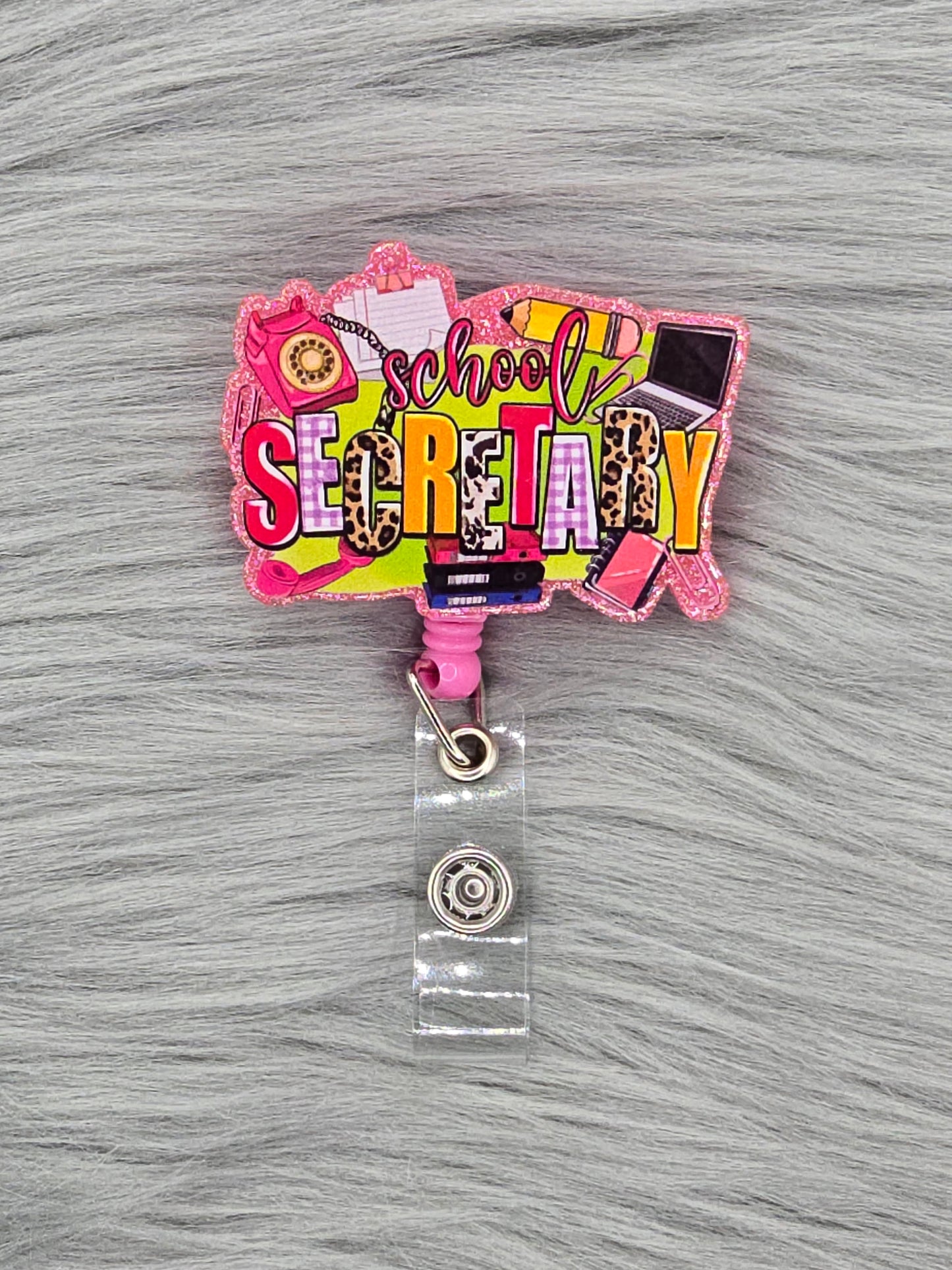 Colorful 'School Secret' acrylic flatback on a pink badge reel