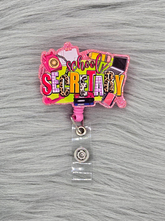 Colorful 'School Secret' acrylic flatback on a pink badge reel