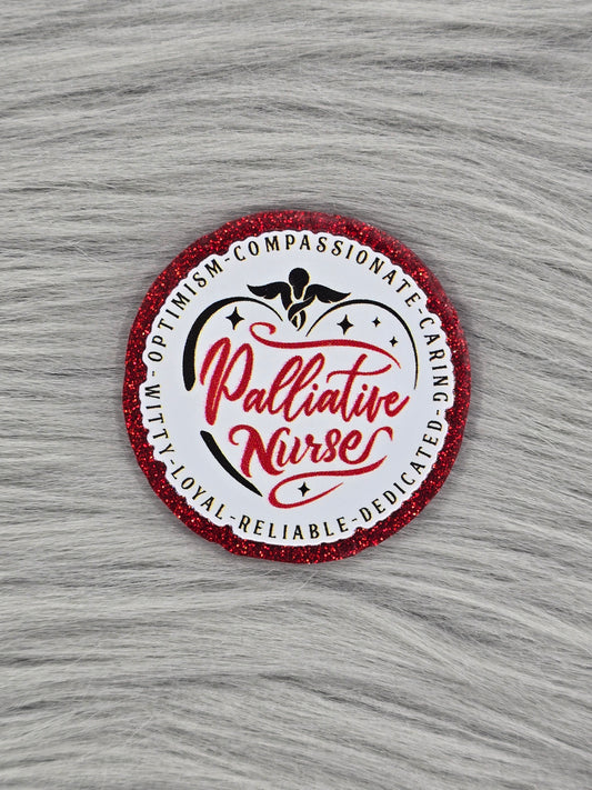 Red glitter flatback with a white background and red words in the middle that say "Palliative Nurse" and on the outside it says" Compassionate, caring, dedicated, reliable, loyal, witty, optimism"