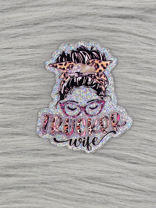 Silver acrylic flatback with a women head with glasses and hair up and the words "Trucker Wife" at the bottom