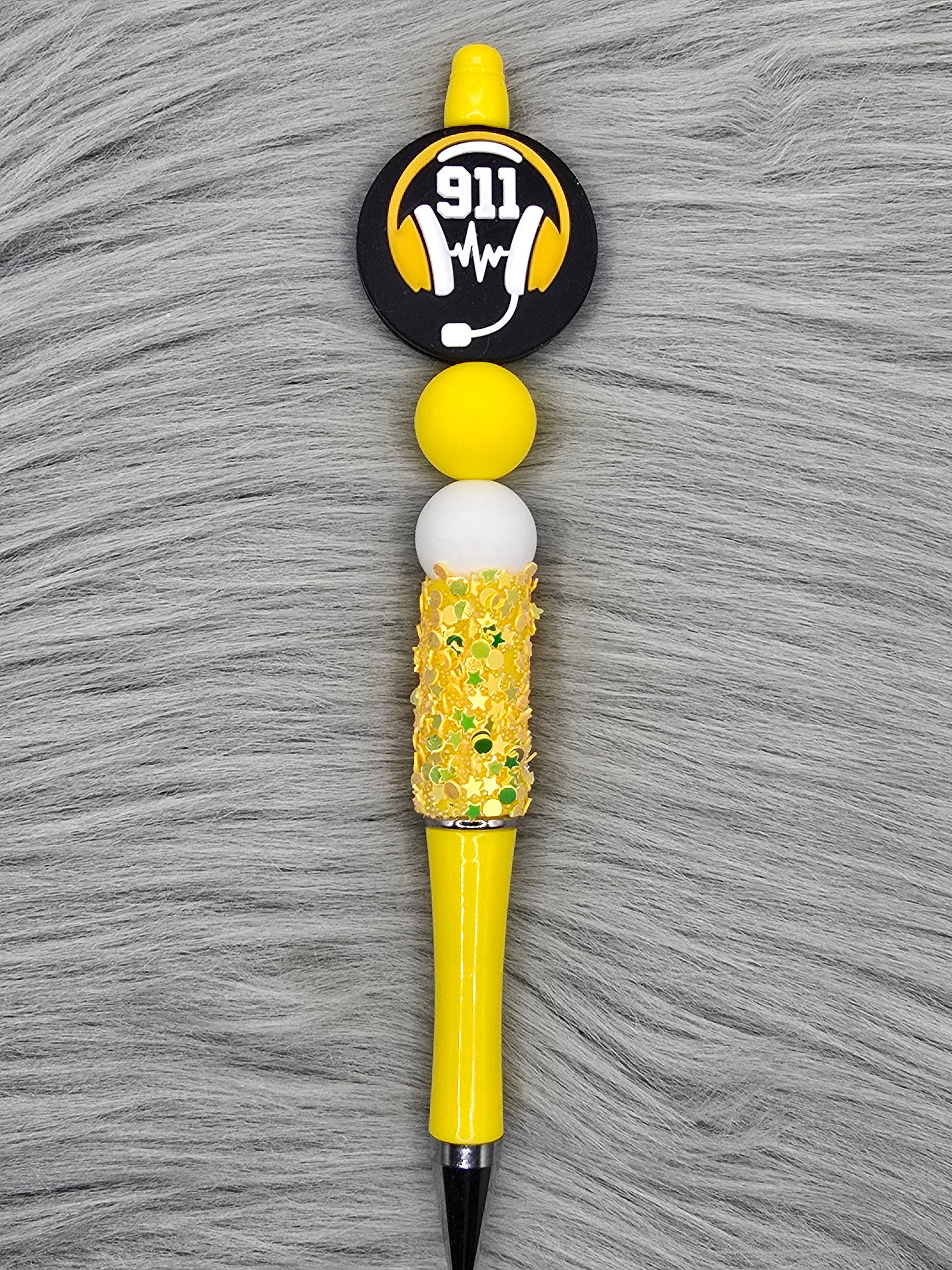 Yellow glitter beadable pen with a silicone focal that says 911 with a headset and a yellow and white bead