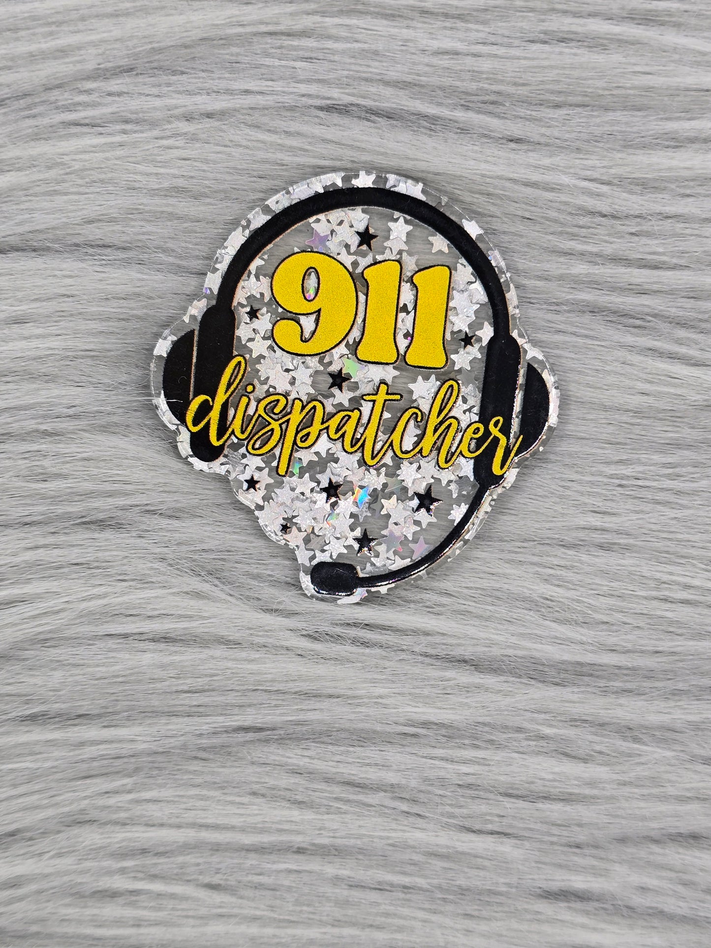 Glitter silver acrylic flatback with the number 911 and the word dispatcher in yellow with a head set