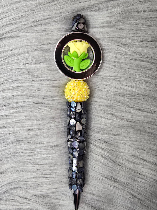 Black beadable pen with pebbles, yellow rhinestone bead with a yellow flower in a black ring at the top