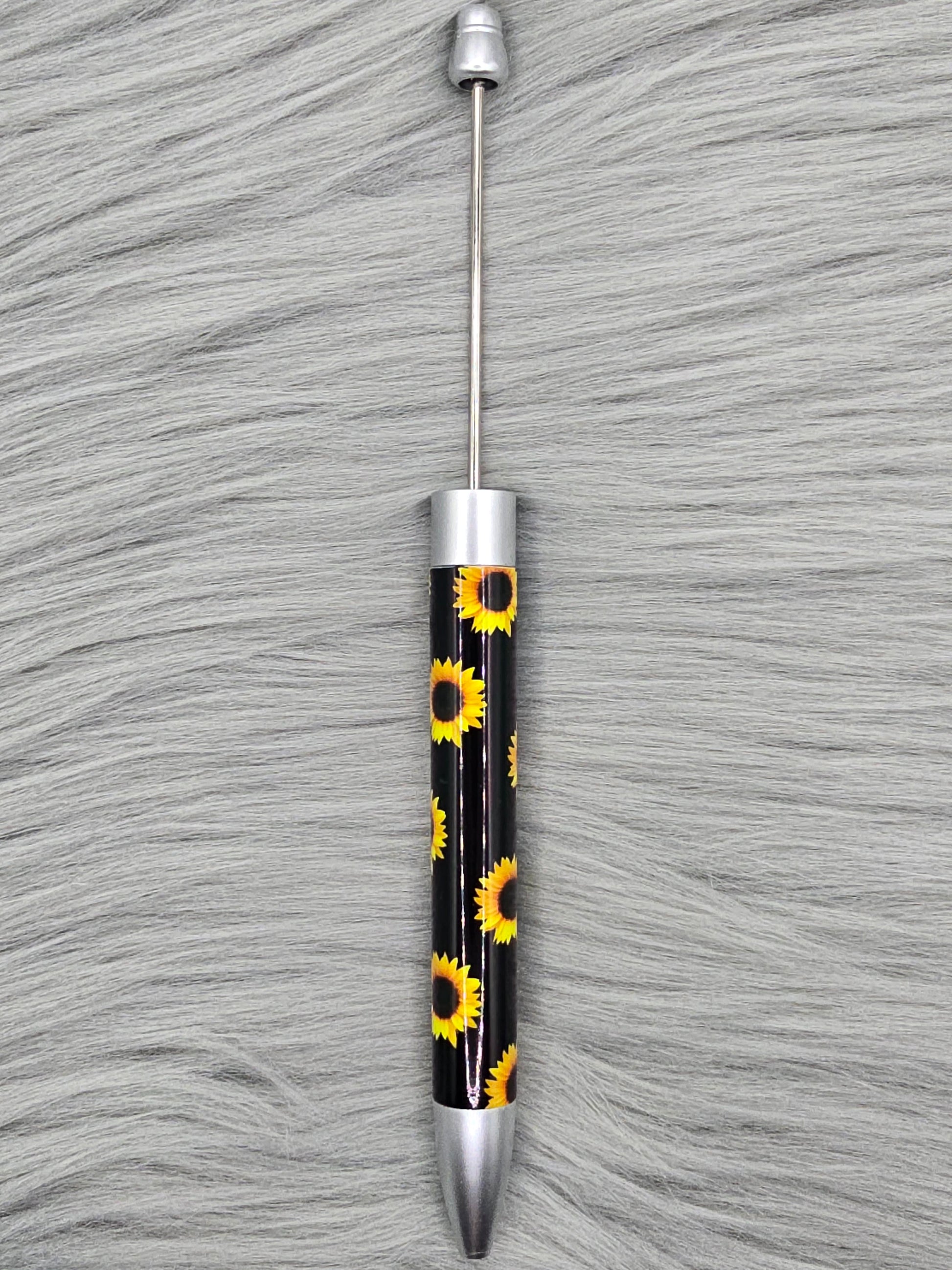 Black beadable pen with sunflower pattern on a gray fur surface