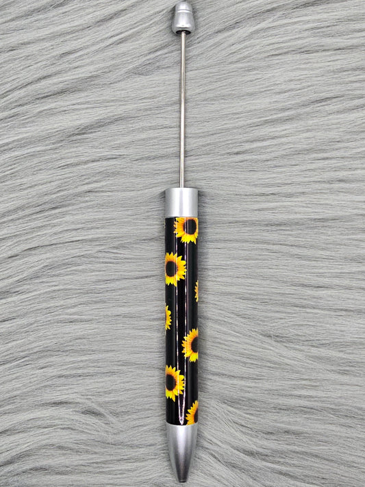 Black beadable pen with sunflower pattern on a gray fur surface