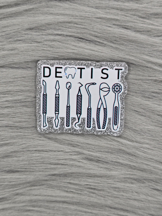 Glitter silver acrylic flatback with a white background and the word Dentist at the top in back and dental equipment under.